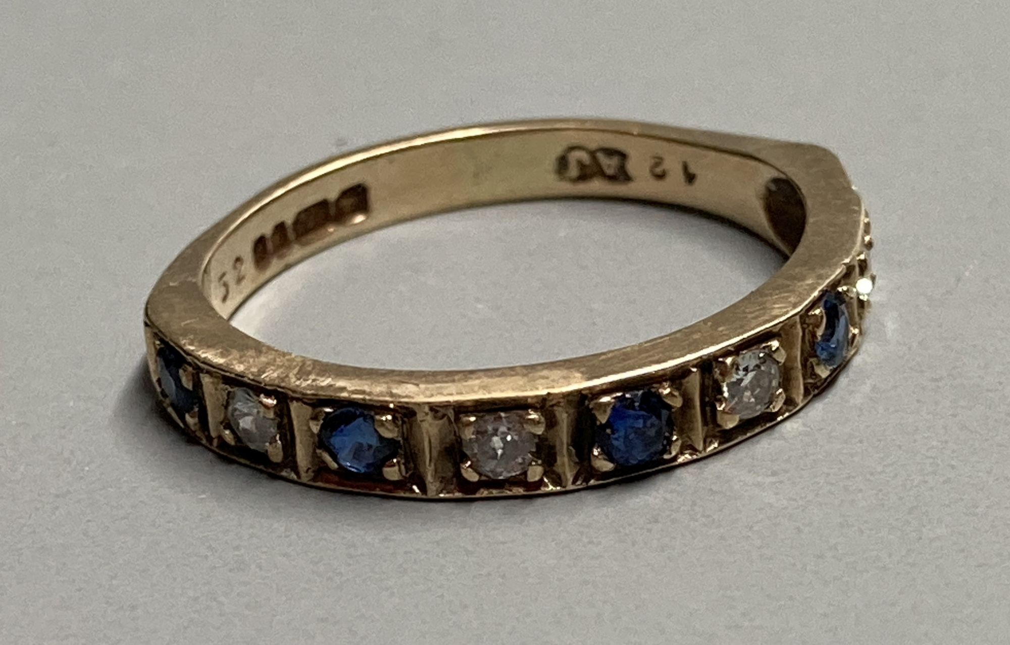 A modern 9ct gold, sapphire and diamond set nine stone half hoop ring, size L, gross 2.3 grams.